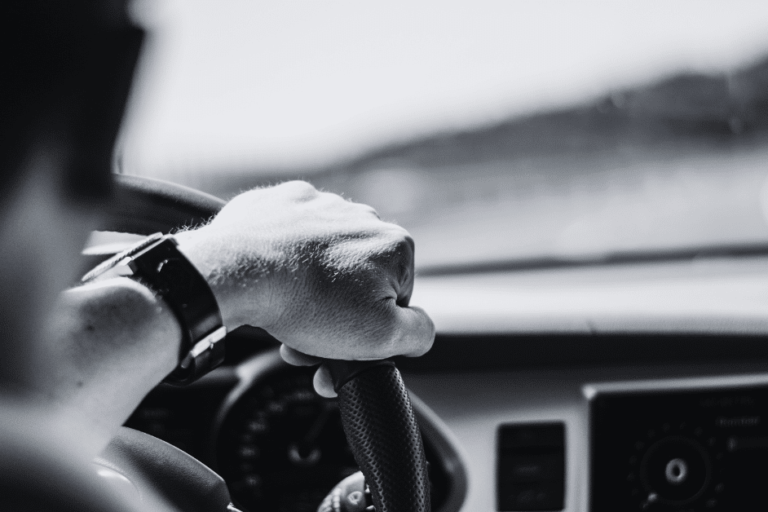 Close up image of the hand of a man behind the wheel while driving