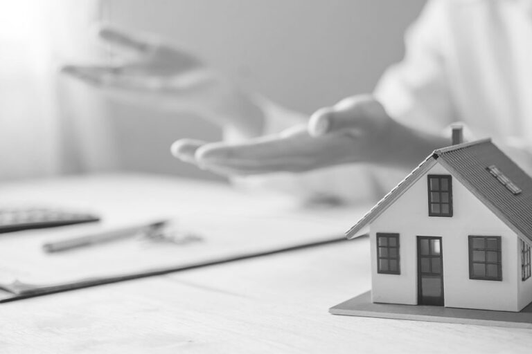 Miniature model of house; Person in background with hands spread