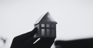 Hand holding a house up with sun shining on it