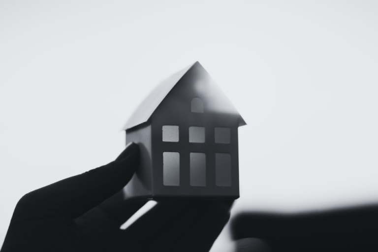 Hand holding a house up with sun shining on it