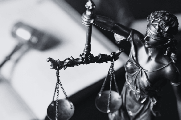 Scales of justice sculpture on desk with gavel