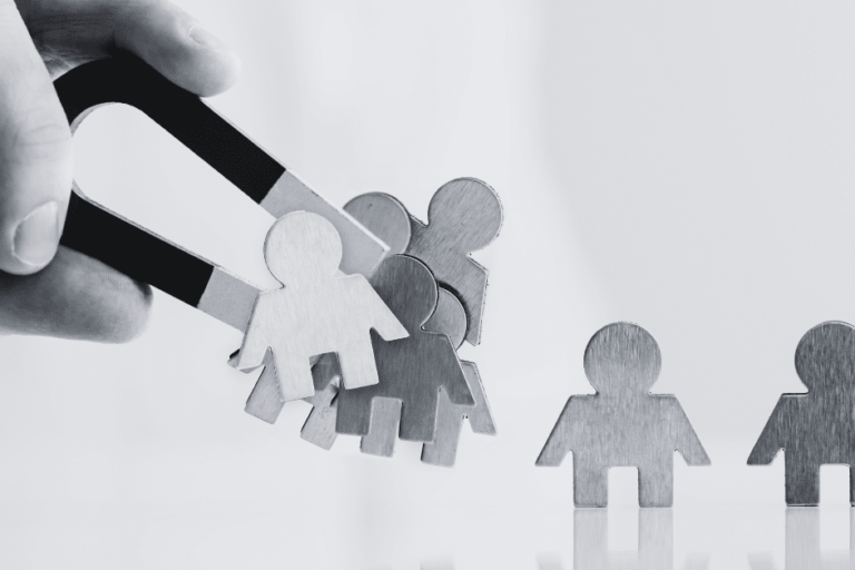 hand holding magnet attracting small figures of people