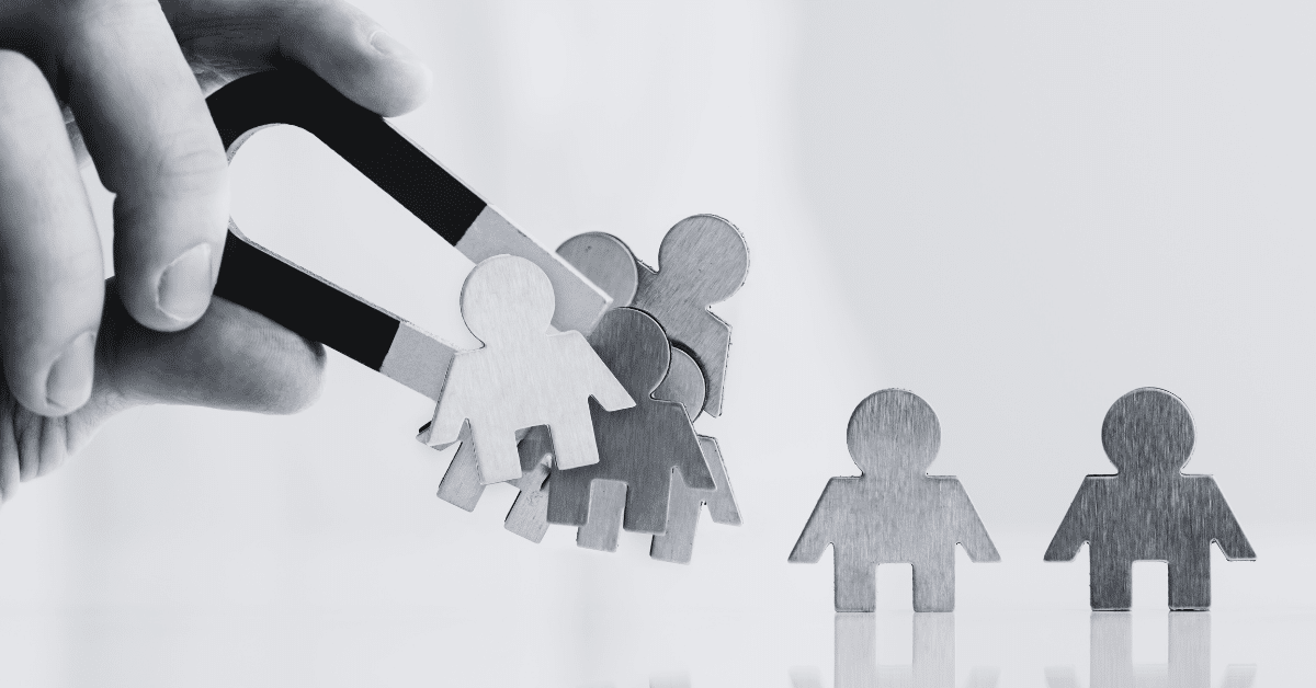 hand holding magnet attracting small figures of people