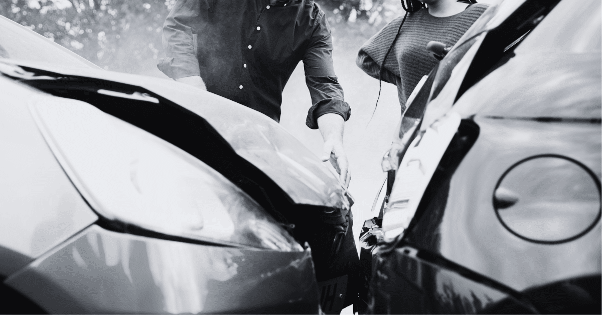 two cars in front end collision and drivers standing by car looking at damage