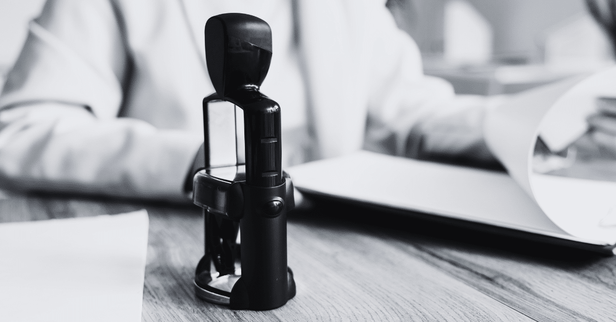 Insurance underwriter assessing application with stamp of approval in center